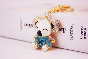 Macro detail of cute koala keychain with blue rhinestones on a golden metal base