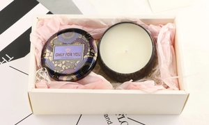 Close-up of scented soy candle in purple tin with gold floral patterns and gift box packaging