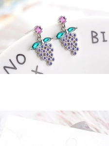 Macro view of purple grape-shaped earrings with sparkling crystals and green leaves