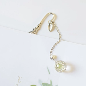 Close-up of metal feather bookmark with real dried flower pendant and pearl detail