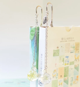 Detail of metal feather bookmark featuring a glass pendant with dried yellow and white flowers
