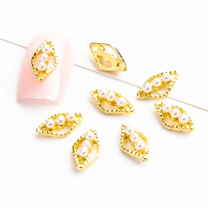 Golden marquise alloy nail charms with three white pearls on minimalist white background