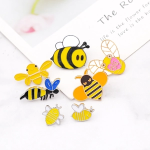 Set of 7 cartoon honey bee enamel pins displayed on marble with BAE heart detail