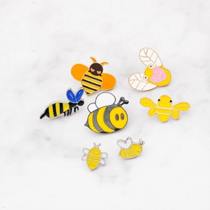 Set of 7 cartoon bee enamel pins in various yellow and black colors on marble background