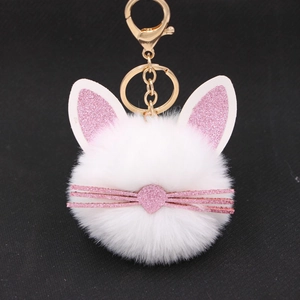 Close-up of white plush kitten keychain with pink glitter ears and gold metal clip