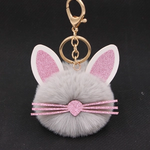 Close-up of gray plush cat keychain with pink glitter ears and whiskers on a black background