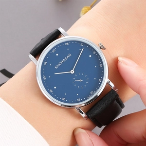 Close-up of minimalist navy blue watch dial with silver case on a female wrist
