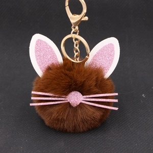 Macro detail of brown plush cat keychain with pink glitter ears and gold metal clip