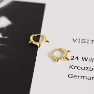 Detailed close-up of a gold spike hoop earring with micro-pave cubic zirconia accents