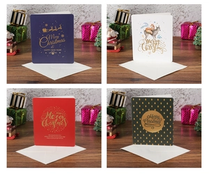 Four festive gold-stamped Christmas cards with envelopes in deep blue, red, green and white