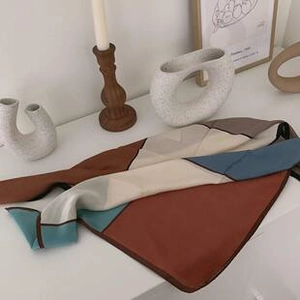 Flat lay of soft satin scarf with geometric pattern in brown, beige, and blue colors