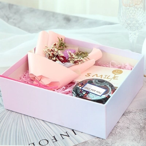Gift box detail showing pink dried flowers, patterned tin can and smile greeting card