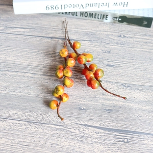 Artificial orange berry branch decoration on wooden background for home interior tabletop decor