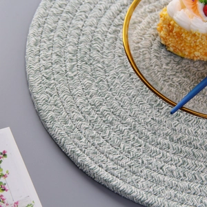 Close-up of circular hand-woven cotton heat resistant placemat in green and beige