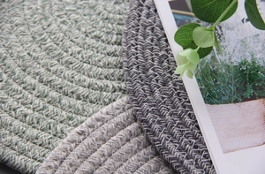 Macro detail of layered woven cotton table mats in light green, beige, and dark grey