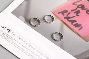 Detail view of S925 sterling silver rings with heart-shaped chain design on a magazine