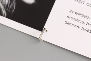 Macro shot of silver heart-shaped ear cuff clipped on a white card with metallic luster