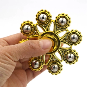 Χρυσό fidget spinner με ασημένιες ατσάλινες μπίλιες που κρατιέται στο χέρι για αποφόρτιση