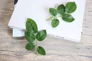 Detailed view of artificial green rose leaves with realistic veins on a wooden table