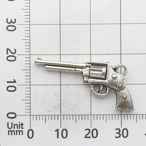 Makro-Detail eines 30mm silbernen Metall-Pistolenanhängers auf einer Rasterskala