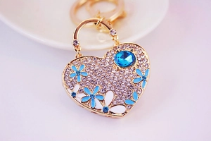 Macro detail of heart-shaped keychain with blue rhinestones and floral enamel finish