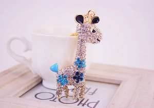 Detailed close-up of golden giraffe keychain with clear crystals and blue enamel details