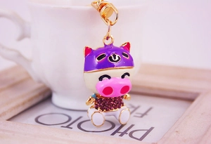 Détail d'un porte-clés cochon avec casque violet orné de strass sur un support en métal doré