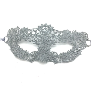 Detail of silver lace masquerade mask with intricate cutout patterns and eye design