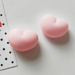 Detail of two pink heart-shaped squishy toys with cute text on a clean background