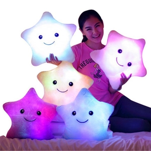 Colorful glowing star plush pillows made of soft velvet material shown on a bed