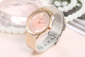 Detail of rose gold mesh band and pink dial watch with elegant pearls and perfume