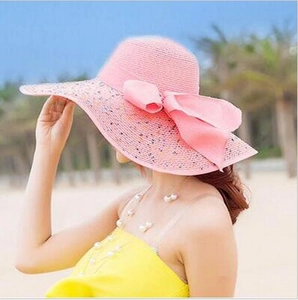 Pink wide-brim straw sun hat with large bow decoration for beach sun protection