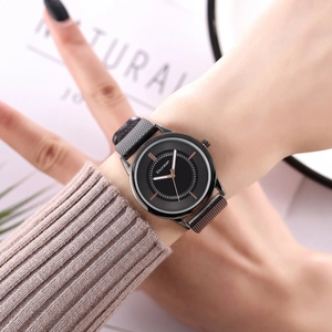 Close-up of elegant black minimalist watch with mesh band worn on a female wrist
