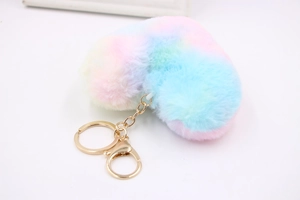 Close-up of rainbow plush heart keychain with gold metal ring on white background