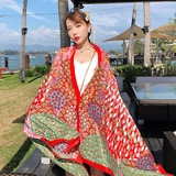 Close-up of red ethnic cotton linen shawl with colorful geometric patterns and fringe detail