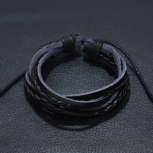 Multi-layer black braided leather bracelet featuring adjustable cord on leather background