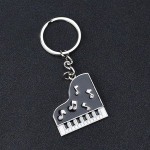 Dettaglio portachiavi a forma di pianoforte in metallo con smalto nero e note con strass