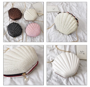 Detail view of shell-shaped crossbody bag with gold chain strap and pearl zipper