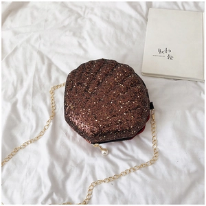 Detail of a brown sequin shell bag with golden chain and pearl zipper pendant