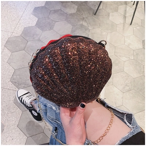 Detail of a scallop-shaped sequin crossbody bag with gold chain strap and glossy finish