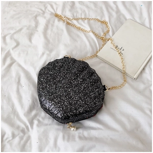 Detail of shell-shaped crossbody bag with black glitter finish and pearl zipper charm