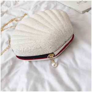 Detail of silver sequin shell bag featuring gold chain and pearl zipper pendant