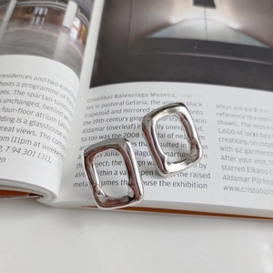 Detailed view of silver rectangular earrings with irregular handmade texture on a magazine