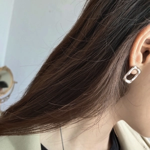 Close-up of minimalist silver rectangular geometric hollow hoop earrings worn by a model