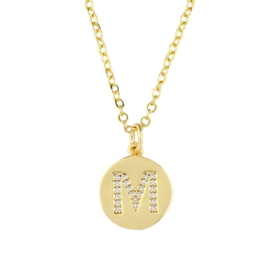 Macro shot of gold-plated pendant featuring a crystal-encrusted letter M on cross chain