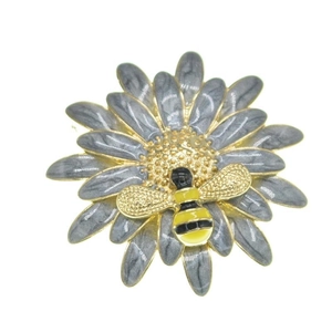 Chic enamel daisy brooch with a gold bee accent on a white background