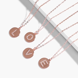 Minimalist rose gold letter pendants L O V E with sparkling zircon on a white stand