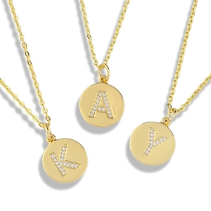 Macro detail of gold round coin necklaces with K, A, Y letters and micro-paved zircons