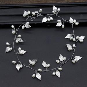 Close-up of silver leaf bridal hair vine with delicate pearls on black textured background