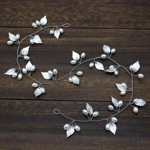 Close-up of handmade silver bridal hair vine with delicate leaves and pearls on wood